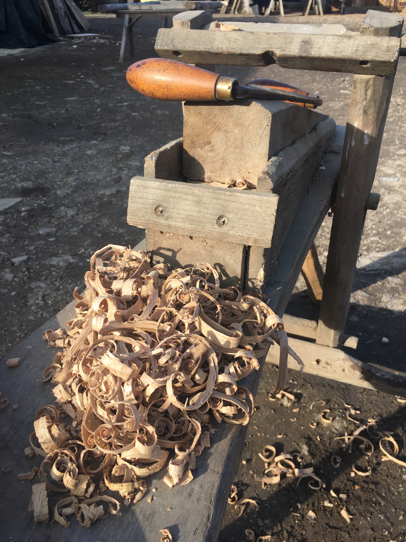 Hand tool beside fresh wood shavings at the wood yard