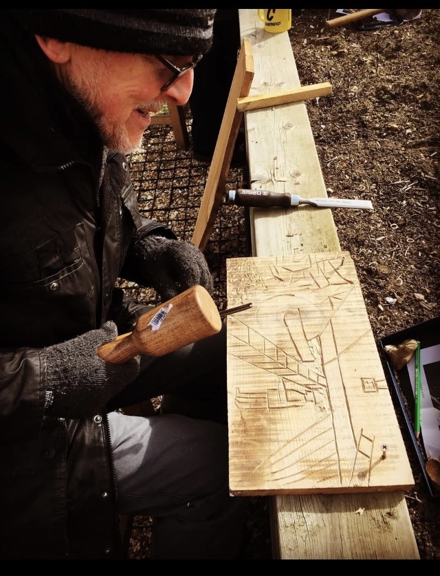 Participant carving a design into a timber panel